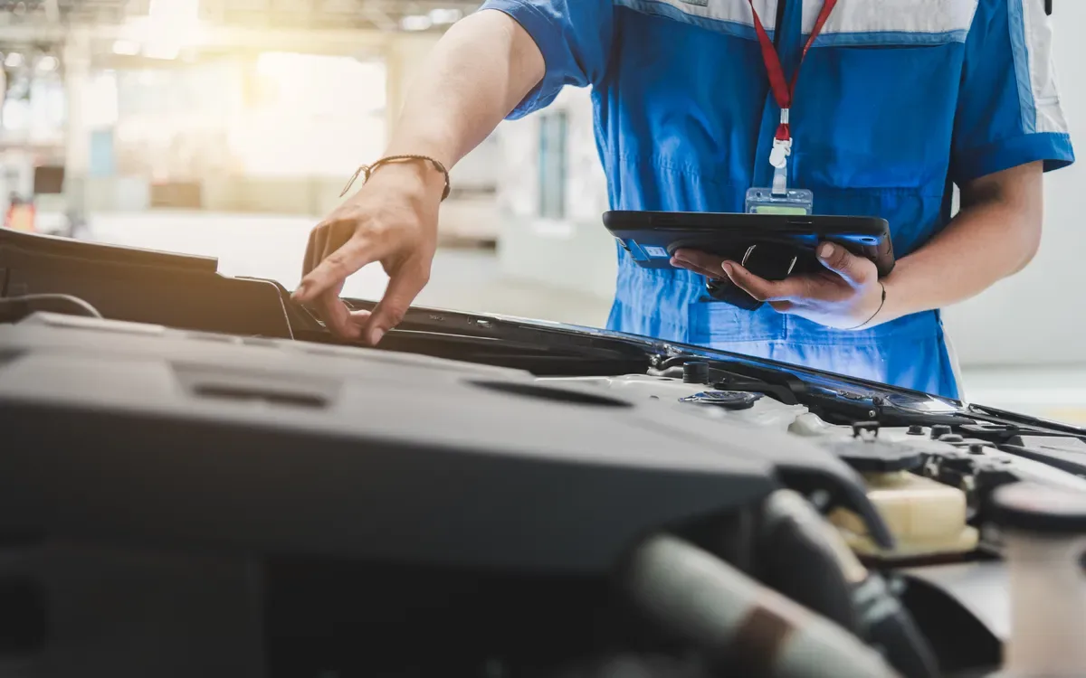 Technicien contrôlant le compartiment moteur d’une voiture